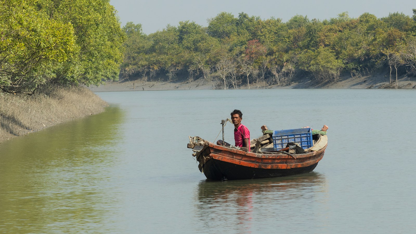A fisherman on a wooden boat on a river in the Sundarbans, West Bengal, near the Bay of Bengal coast where fishermen were ordered off the water during this week's storm