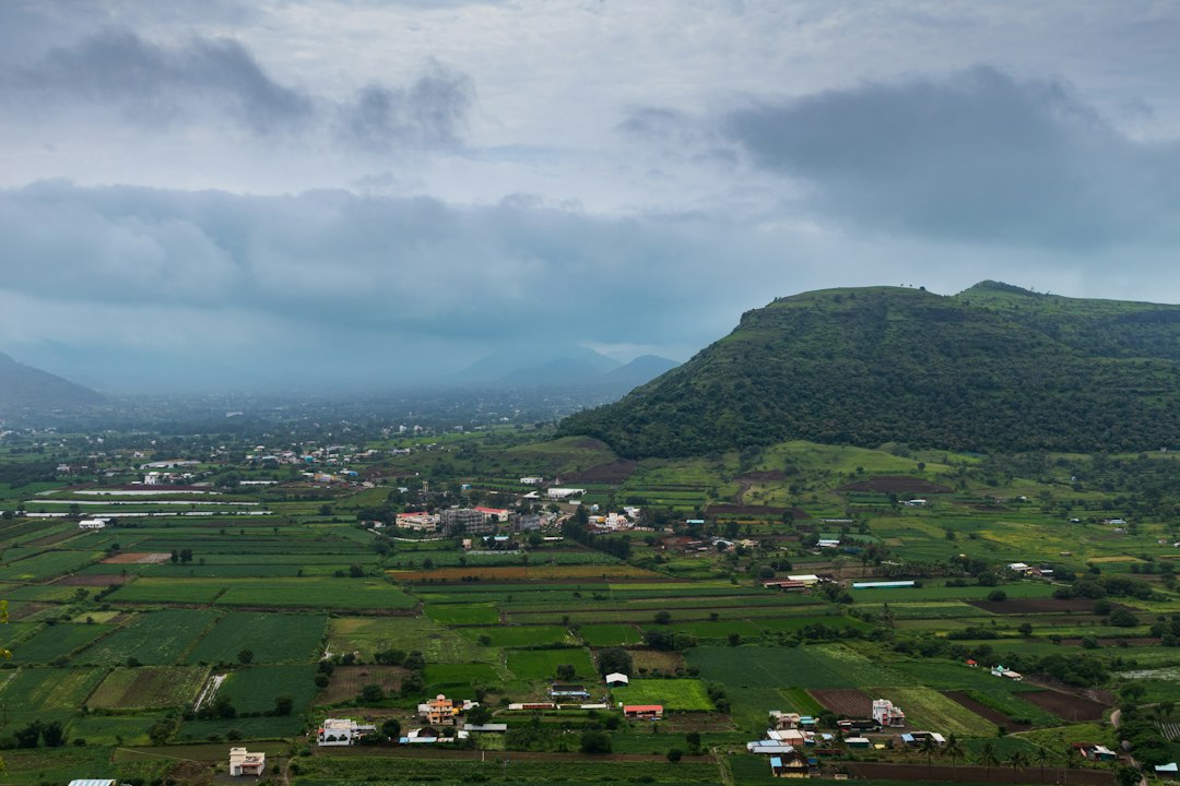 Grey monsoon clouds over green fields and a village in India as the 2026 southwest monsoon begins its withdrawal