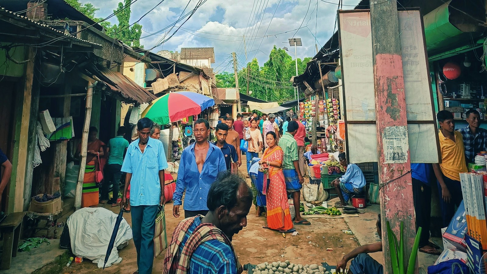 A crowded street market in Northeast India with vendors selling produce and goods from small shopfronts