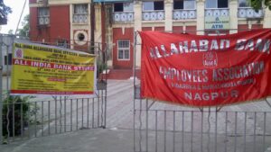 A red banner reading Allahabad Bank Employees Association AIBEA and a yellow All India Bank Strike notice from the United Forum of Bank Unions, tied to the gate outside a shuttered Allahabad Bank branch in Nagpur