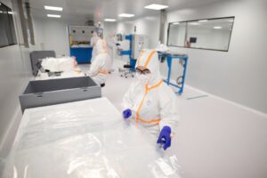 Workers in cleanroom protective suits handling equipment inside a semiconductor fabrication facility
